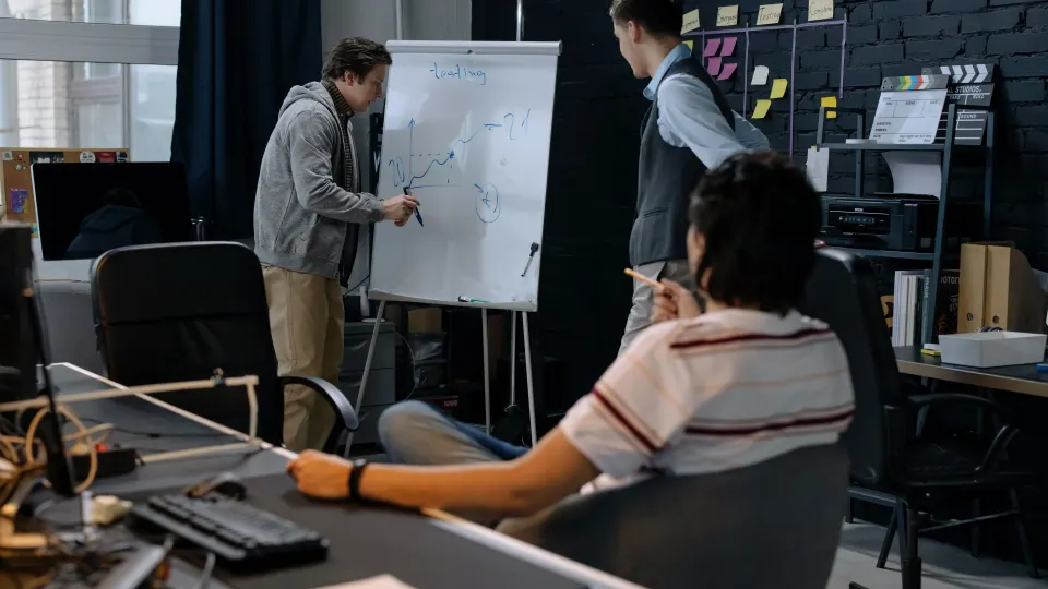 A team discussing business challenges and opportunities around a whiteboard