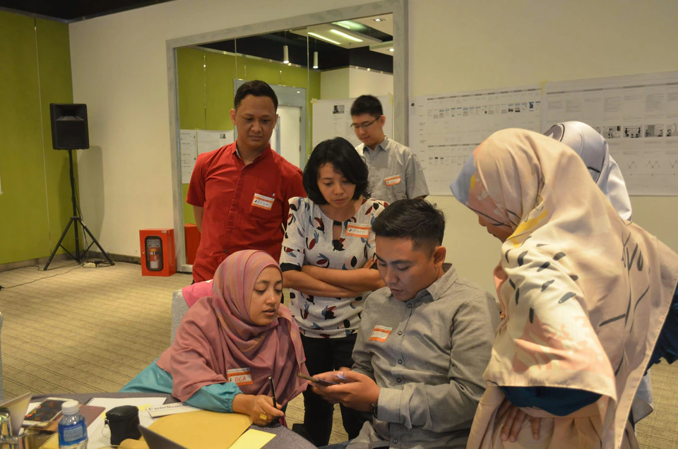 Men and women collaborating during a hands-on Indonesian team workshop.